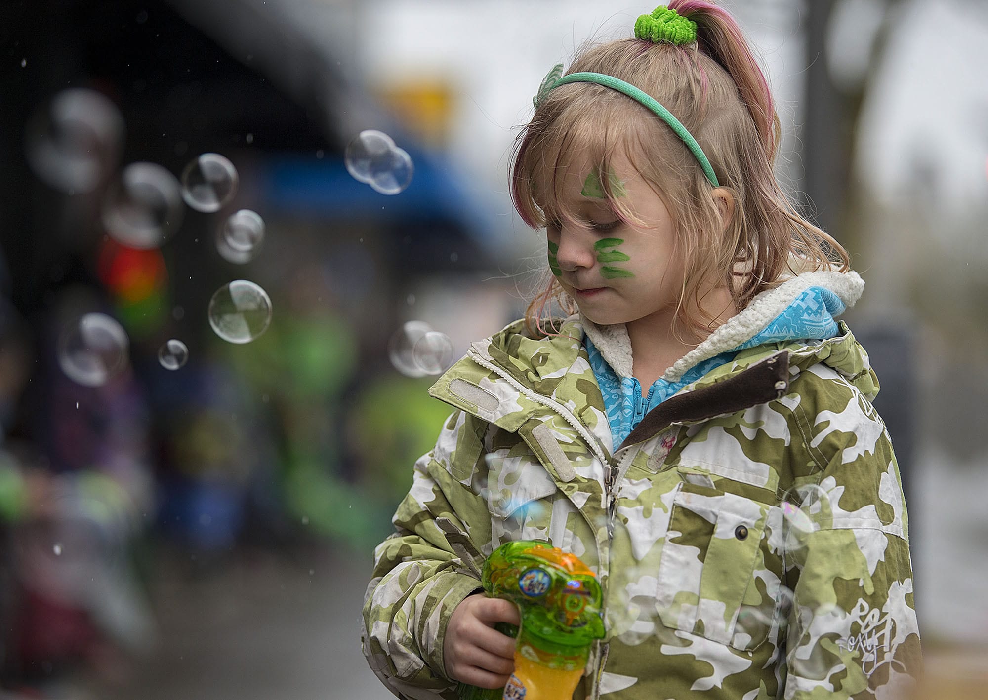 Six-year-old Abbygale Harris of Vancouver gets into the spirit of the holiday with festive green face painting and bubbles while waiting in Uptown Village for the annual Paddy Hough Parade to start Friday afternoon, March 17, 2017.