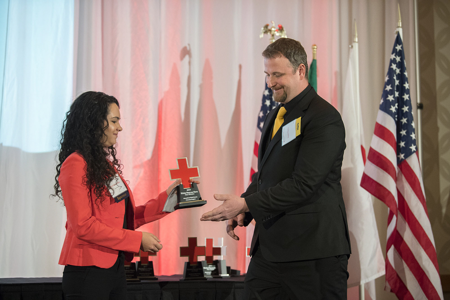 Mariah Gonzales of Fred Meyer, left, hands the Water Rescue Hero award to Dan Windon at the annual American Red Cross Heroes Breakfast event Friday morning. Windon is credited with saving the life of a motorist whose car had become completely submerged in water.
