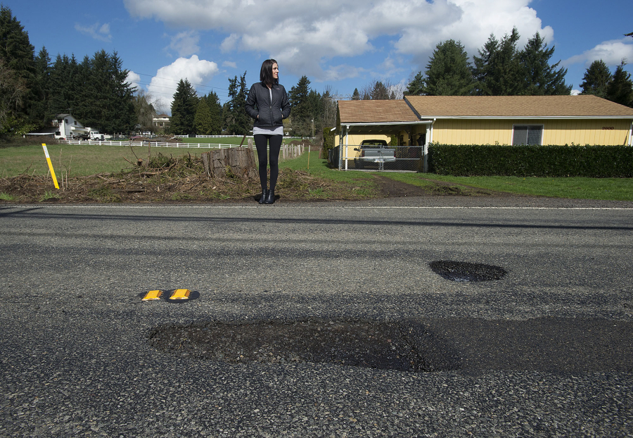 Vancouver resident Teresa Eldred stands near a pothole along Northeast 68th Street that she said popped her tire and damaged her rim early last month. She filed a tort claim against the county to recoup her costs but was denied --  like most everyone else who files claims against the government about pothole damage.