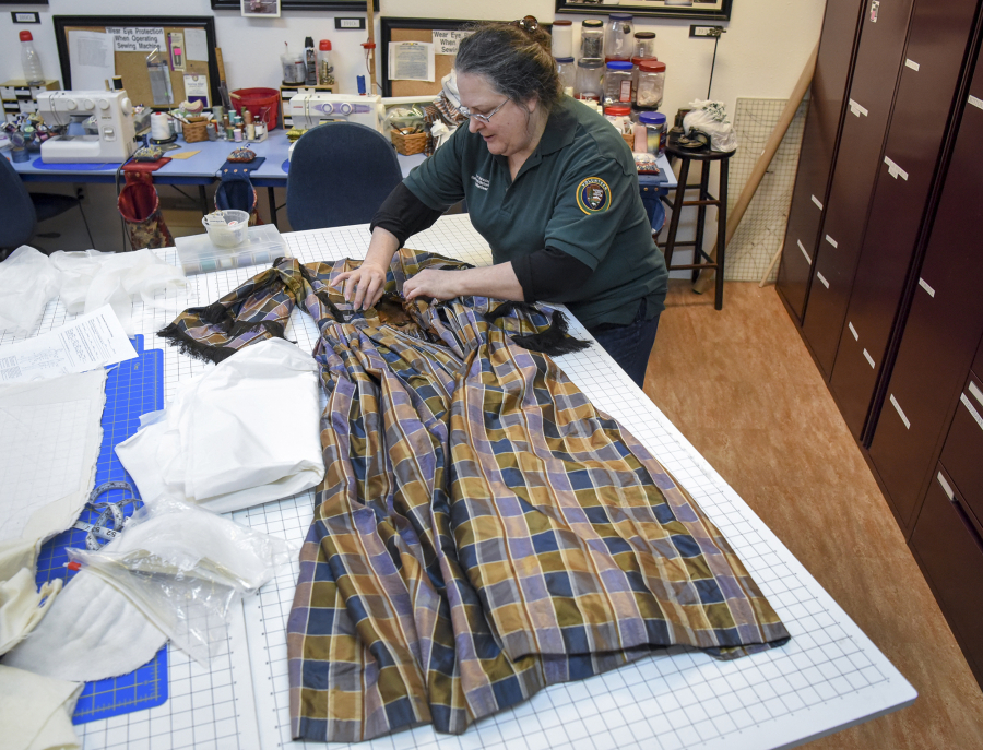 Eileen Trestain, who manages the costume department at Fort Vancouver, examines a silk dress that was made around 1850. It had belonged to Maria Barclay, whose husband, Dr. Forbes Barclay, was the physician at Fort Vancouver during the 1840s.