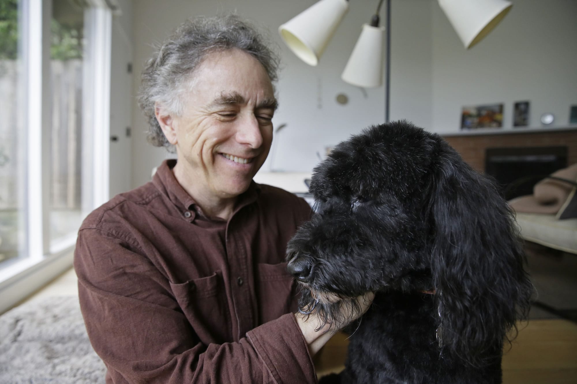 In this photo taken Wednesday, Feb. 15, 2017, Michael Fasman poses with his dog Hudson at his home in San Francisco. As more states legalize marijuana for humans, more pet owners are giving their furry companions cannabis-based extracts, ointments and edibles marketed to treat everything from arthritis and anxiety to seizures and cancer.
