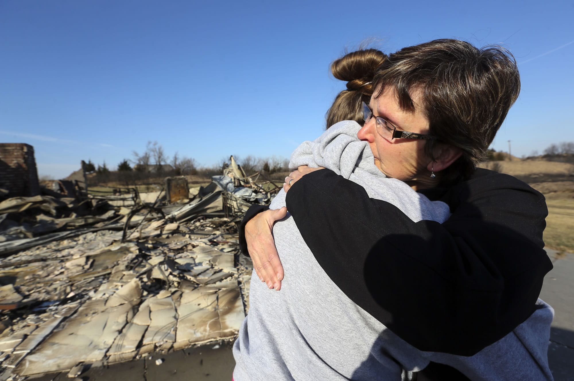 Zane Jackson embraces her daughter, Shelby Jackson, as they arrive to see their destroyed home for the first time in the Highlands subdivision on Wednesday, March 8, 2017, in Hutchinson, Kan. The home was destroyed in the wildfires Monday night.