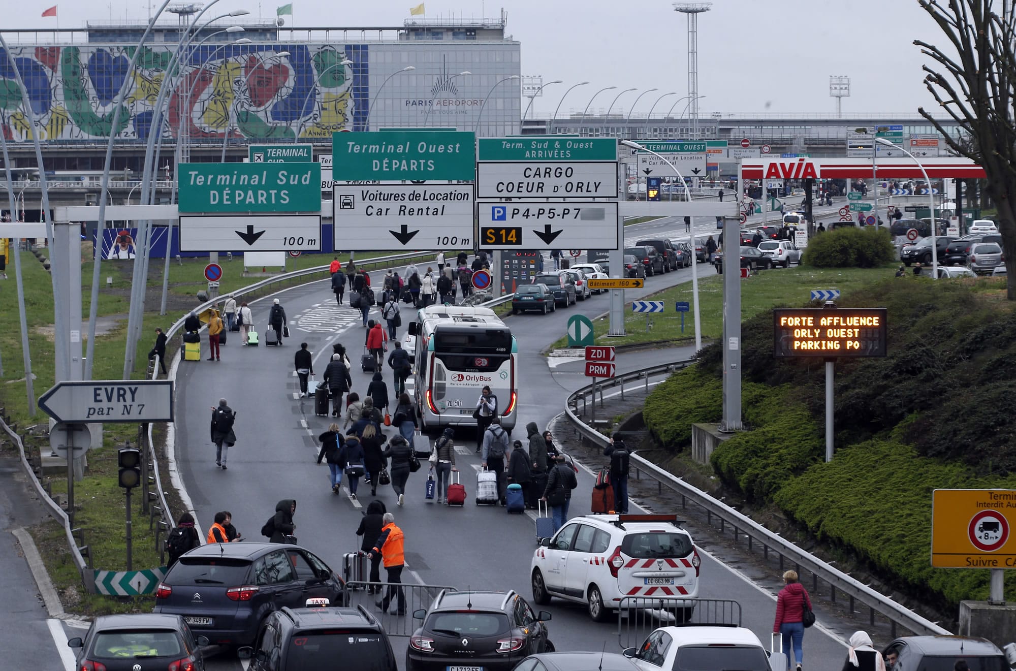 Travellers walk on the highway to the Orly airport, south of Paris, Saturday, March, 18, 2017. A man was shot to death Saturday after trying to seize the weapon of a soldier guarding Paris' Orly Airport, prompting a partial evacuation of the terminal, police said.