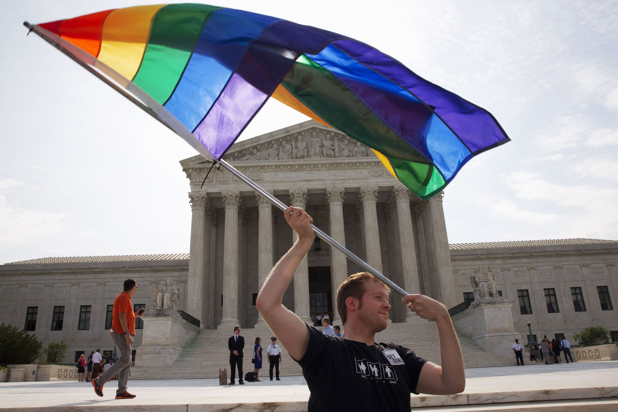 FILE - In a  June 25, 2015 file photo, John Becker, 30, of Silver Spring, Md., waves a rainbow flag in support of gay marriage outside of the Supreme Court in Washington. LGBT advocates are questioning the Trump administration’s quiet deletion of questions on sexuality from two federal surveys.