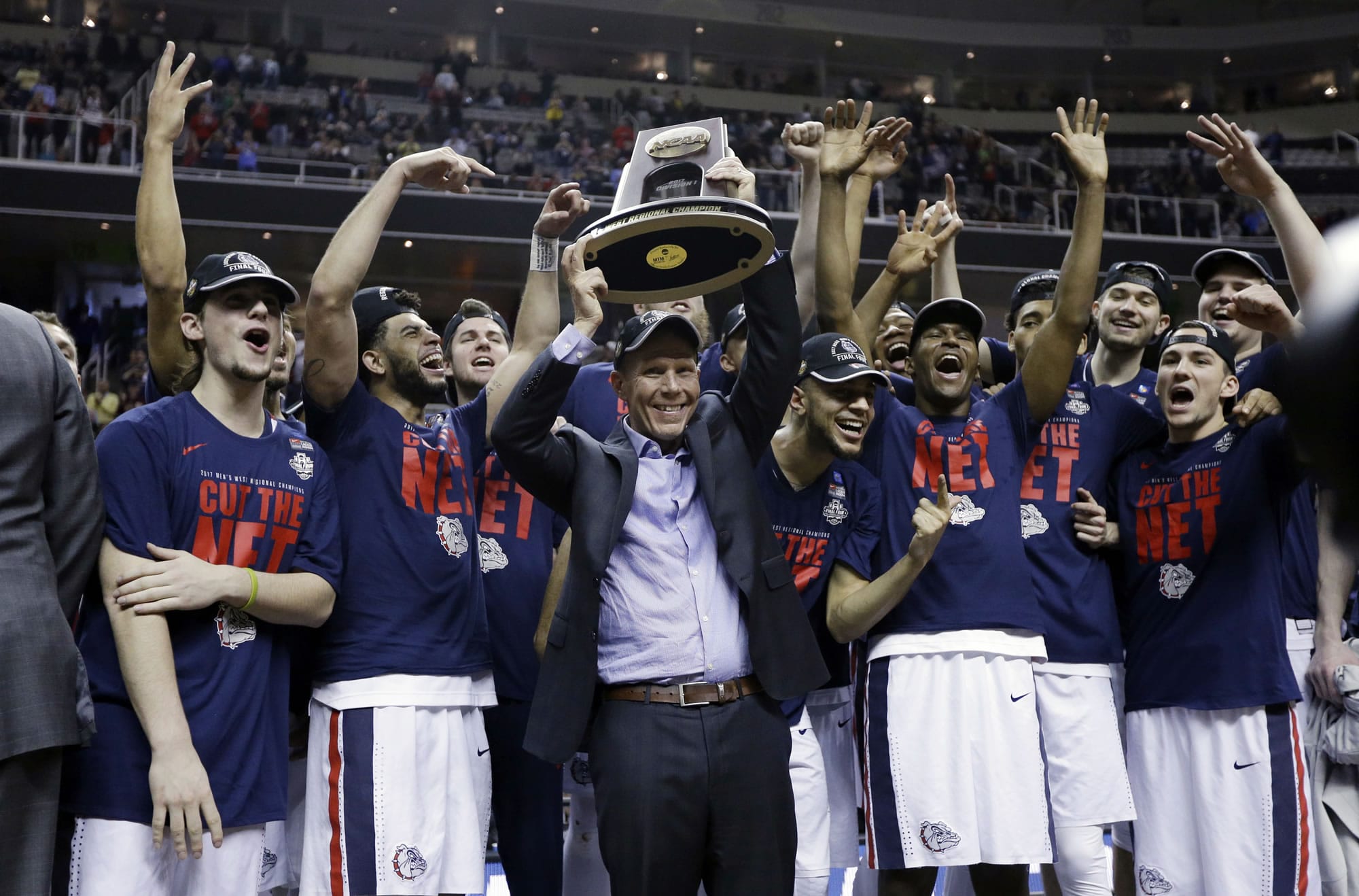 Gonzaga head coach Mark Few, center, holds a trophy as his players surround him after a win over Xavier in an NCAA Tournament college basketball regional final game Saturday, March 25, 2017, in San Jose, Calif.