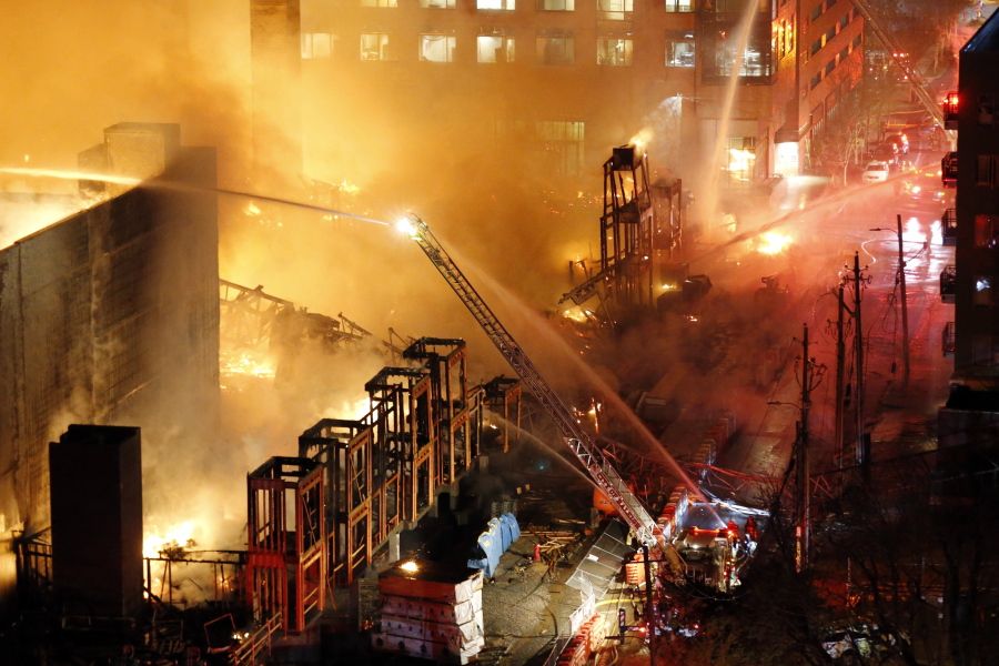 Firefighters battle a five-alarm fire burning an apartment building and surrounding structures in downtown Raleigh, N.C., on Thursday night. Fire was consuming an apartment building under construction. The cause of the fire is under investigation.