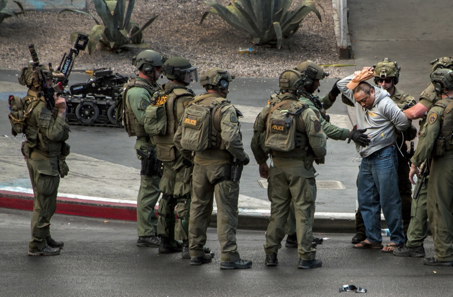 A suspect surrenders to SWAT officers after being barricaded for many hours on a bus after a fatal shooting in the vehicle earlier today which down the busy tourism corridor near the Cosmopolitan hotel-casino in Las Vegas on Saturday. Las Vegas Police officer Larry Hadfield said just before 3:30 p.m. that the man had a handgun and surrendered without incident.  (L.E.