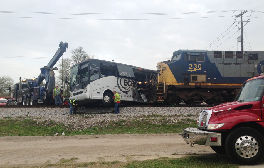 Men prepare to move a charter bus after a freight train crashed into the bus in Biloxi, Miss., on Tuesday. The freight train smashed into the charter bus in the coastal Mississippi city on Tuesday, pushing the bus 300 feet down the tracks and leaving several people dead, authorities said.