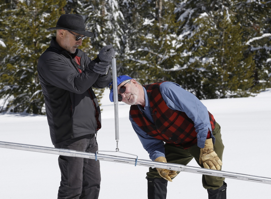 Frank Gehrke, right, chief of the California Cooperative Snow Surveys Program for the Department of Water Resources, checks the weight of the snowpack on a scale held Wednesday by Armando Quintero, chairman of the California Water Commission, during the third manual snow survey of the season at Phillips Station near Echo Summit, Calif.