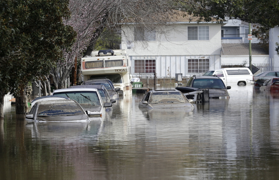 Submerged automobiles are shown on flooded Nordale Avenue in San Jose, Calif., Wednesday, Feb. 22, 2017. Rising floodwaters sent thousands of residents fleeing inundated homes in San Jose and forced the shutdown of a major freeway Wednesday.