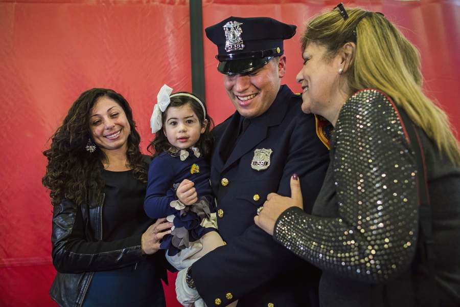 Matias Ferreira, center, celebrates with his 2-year-old daughter, his wife, left, and his mother Friday during his graduation from the Suffolk County Police Department Academy in Suffolk, Long Island, N.Y.