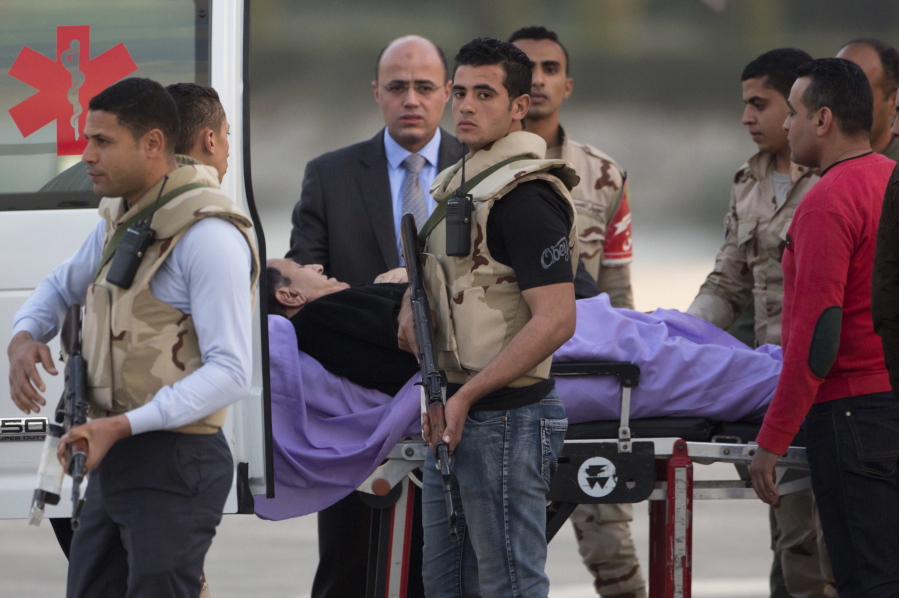 Ousted Egyptian President Hosni Mubarak is escorted by medical and security personnel into an ambulance Thursday at Maadi Military Hospital in Cairo, where he is hospitalized, after an ambulance helicopter landed from the Cairo Police Academy-turned-court.