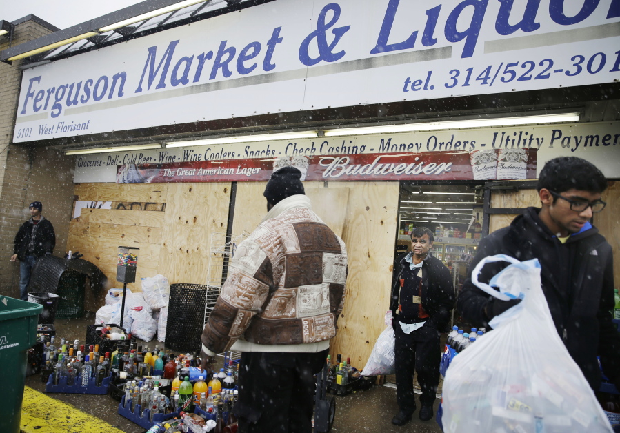 Kush Patel, right, carries out bags of merchandise in November 2014 while helping his uncle Andy Patel, rear, clean up the looting damage from riots at his store, Ferguson Market and Liquor, in Ferguson, Mo. The store is disputing a new documentary's claims that surveillance video suggests Michael Brown didn't rob the store before he was fatally shot by police in Ferguson. One of the filmmakers said he believes the footage shows Brown trading marijuana for a bag of cigarillos early on Aug. 9, 2014, and that Brown intended to come back later for the cigarillos. Store officials said no drug transaction took place and Brown stole the cigarillos while at the store later that day.