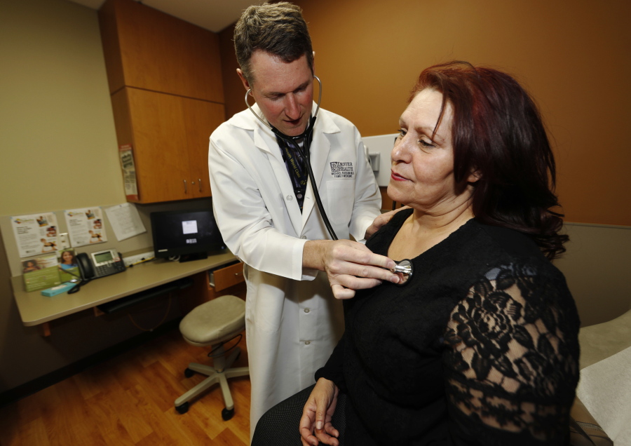 Dr. Michael Russum, left, checks patient Ruby Giron on Thursday in Denver Health Medical Center&#039;s primary care clinic located in a low-income neighborhood in southwest Denver.