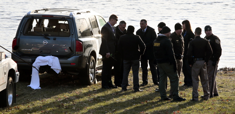 Law enforcement officials work Thursday beside Silver Lake in Highland, Ill., near an SUV that was found in the water with a baby inside. (robert cohen/St.