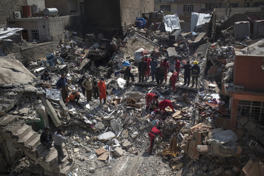 FILE - In this Friday, March 24, 2017, file photo, civil protection rescue teams work on the debris of a destroyed house to recover the body of people killed during fighting between Iraqi security forces and Islamic State militants on the western side of Mosul, Iraq. Iraqis in the northern city of Mosul are still burying their dead after a U.S. airstrike allegedly killed more than 100 people last week, and rights groups are expressing alarm over a recent spike in civilian deaths. Iraqi officials have defended their conduct in the war against the Islamic State group, and their advice to civilians to shelter in place as U.S.-backed forces seek to drive the extremists from their last urban stronghold in the country.