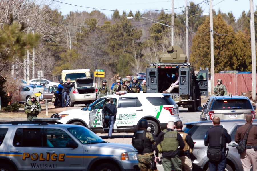 Numerous law enforcement vehicles and SWAT teams respond to shooter Wednesday, March 22, 2017, at an apartment complex in Rothschild, Wis. The shootings happened at a bank, a law firm and an apartment complex, where officers, including a SWAT team, were in a standoff with the suspect late in the afternoon, Wausau police Capt. Todd Baeten said at a news conference. The area is about 90 miles west of Green Bay.