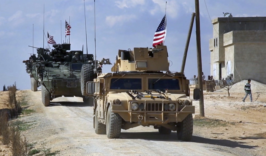 In this image from video taken Tuesday, U.S. forces patrol on the outskirts of the Syrian town of Manbij, a flashpoint between Turkish troops and allied Syrian fighters and U.S.-backed Kurdish fighters in Aleppo province.