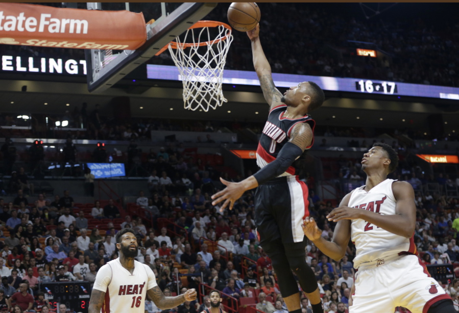 Portland Trail Blazers&#039; Damian Lillard (0) dunks over Miami Heat&#039;s James Johnson (16) and Hassan Whiteside (21) during the first half of an NBA basketball game, Sunday, March 19, 2017, in Miami.