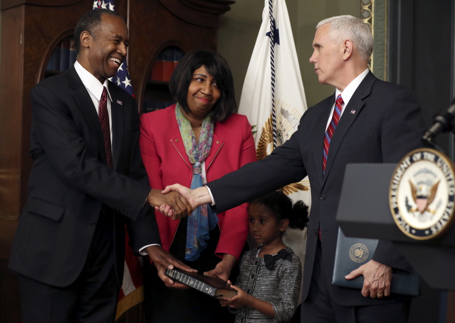 Vice President Mike Pence, right, shakes hands with Housing and Urban Development Secretary Ben Carson after the oath of office as his wife, Candy, and granddaughter Tesora Carson, 5, hold the Bible on Thursday in Washington.