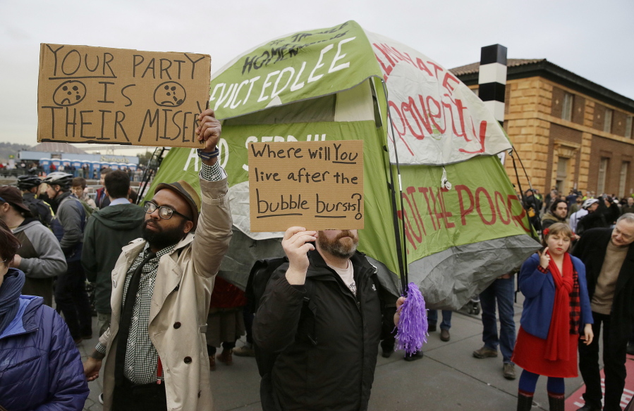 People hold up signs and a tent Feb. 3 during a protest to demand city officials do more to help homeless people outside Super Bowl City, a weeklong football theme park near the Ferry Building in San Francisco.