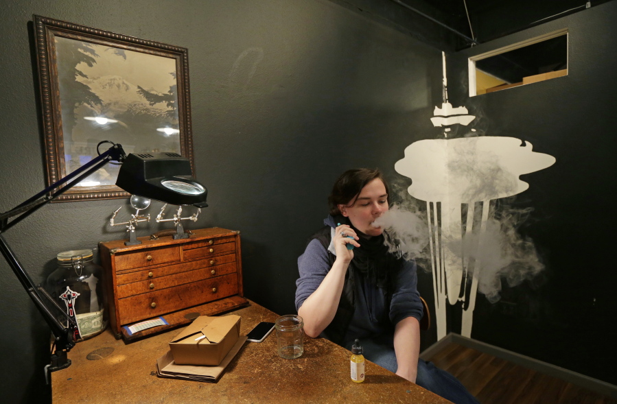 In this March 15, 2017, photo, Becca Blackwell vapes after taking a lunch break in the Future Vapor store in Seattle. Lawmakers in the Washington state Legislature are proposing a tax on vapor products, e-cigarettes and other nicotine products. (AP Photo/Ted S.