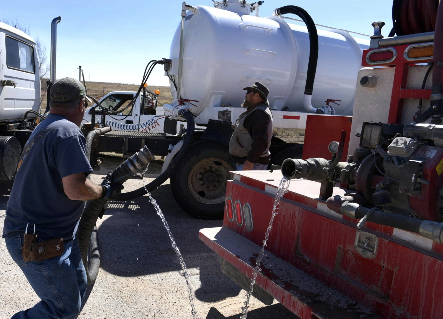 Gray County crew members Duck Wright and Erik Schindler pump water onto Hoover Volunteer fire trucks north of McLean, Texas, Tuesday.