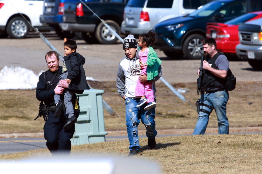 Police officers escort a family from an apartment complex to safety Wednesday in Rothschild, Wis.