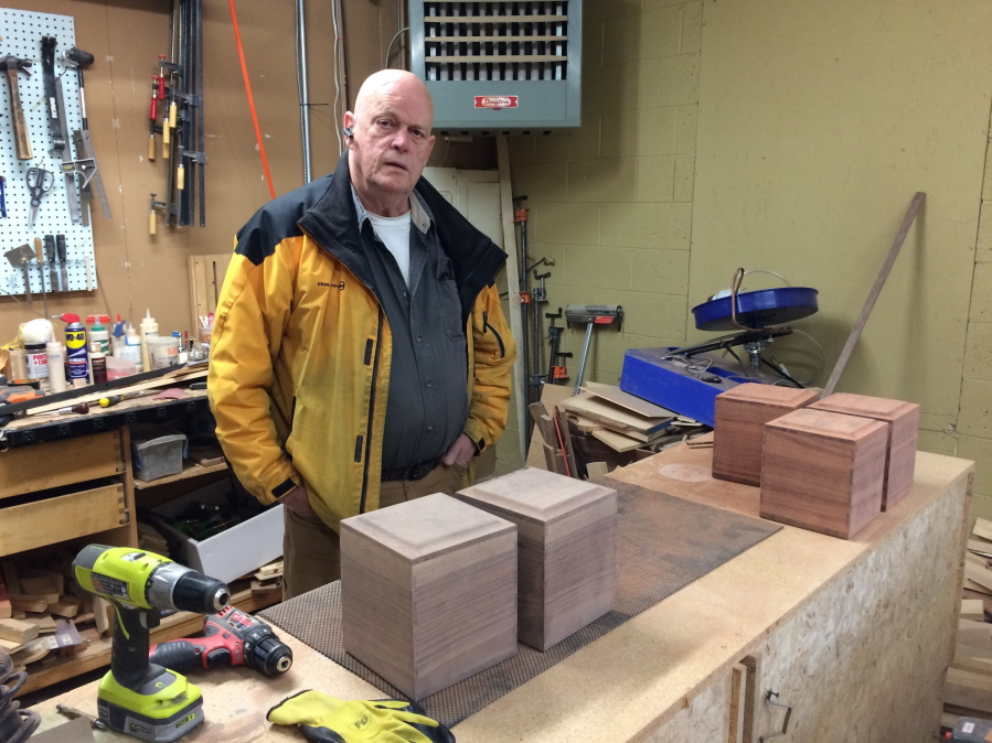In this March 2017 photo, woodworker Danny Minor poses near hand-crafted wood urns he made at his shop in The Dalles, Ore.