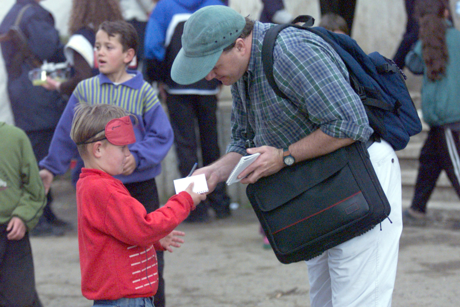 Brian Willoughby gives a Kosovar refugee boy a pen and paper at the Sports Palace in Korce, Albania, in 1999.