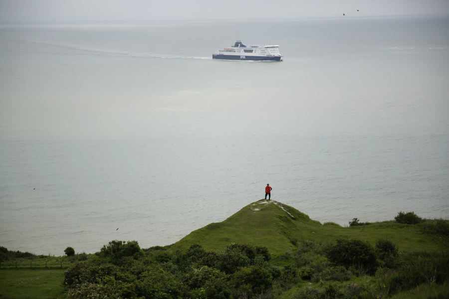 A tourist looks out from a section of the White Cliffs of Dover in southeast England toward the Strait of Dover, the narrowest point of the English Channel, which separates Britain from mainland Europe.