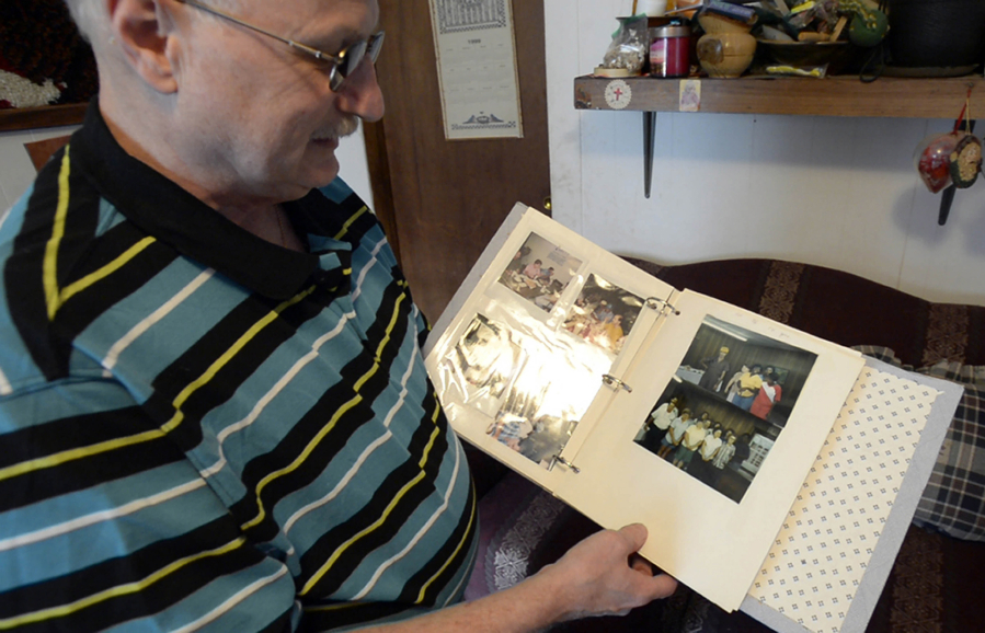 Scot Wilson shows a scrap book of photos from his work, while at his home  in Maiden, N.C. Wilson worked at the Delta Apparel facility across the street from his house for nearly 40 years. (David T.