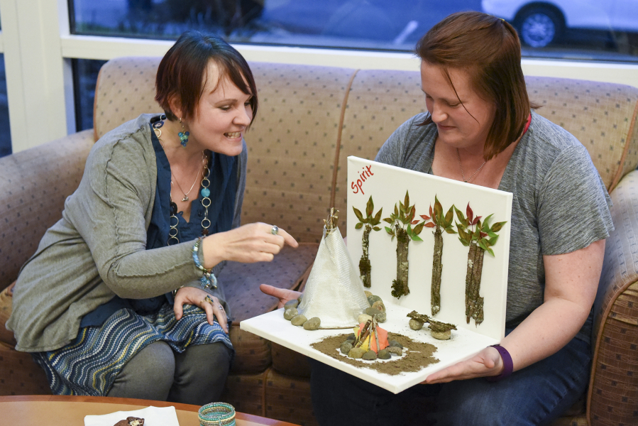 Monika Spykerman, left, looks at Jamie Morris&#039; artistic project, based on scenes and themes from the book &quot;The Interestings,&quot; by Meg Wolitzer, during book club at the Camas Public Library.