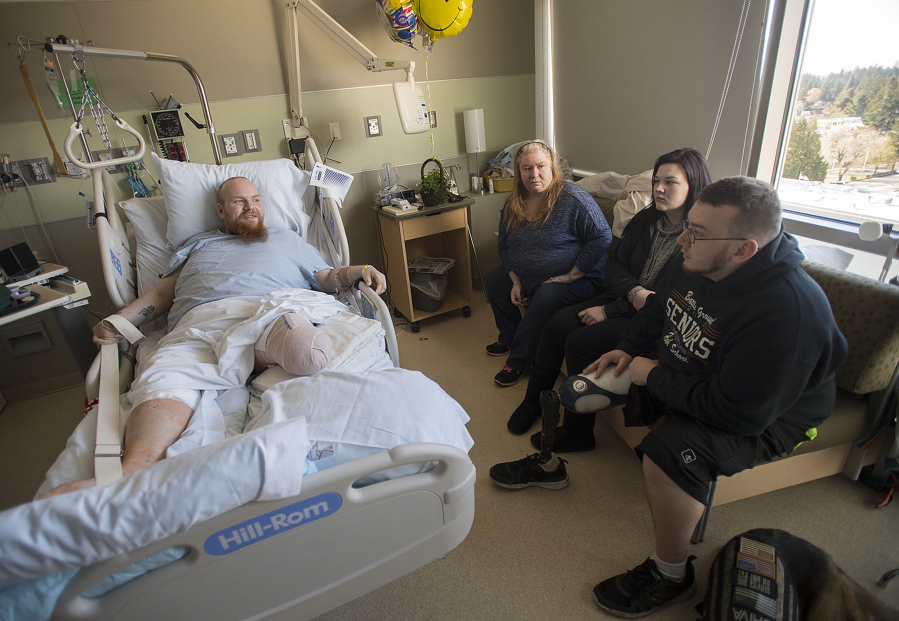 Paul Adams, clockwise from left, talks with his mom, Nancy Peterson, Jaden Carey and her brother, Justin Carey, during a hospital visit at PeaceHealth Southwest Medical Center on Monday. Adams and Carey both lost a leg after allegedly being struck by drivers from the same family.