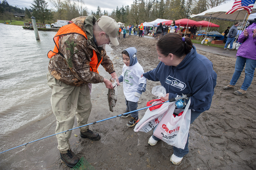 Volunteer Paul Pfeifer, from left, helps Alexander Nihipali, 5, and his mom, Leilani, catch a 23-inch, 6-pound rainbow trout during the annual Klineline Kids Fishing Derby. It was the biggest fish caught during the 9 a.m. hour on Friday.