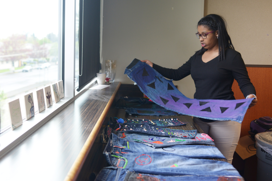 Alayah Willis, 13, holds a pair of jeans she decorated as part of the blue jean project at the Boys &amp; Girls Clubs O.K. Clubhouse. She said she painted triangles because they looked cool.