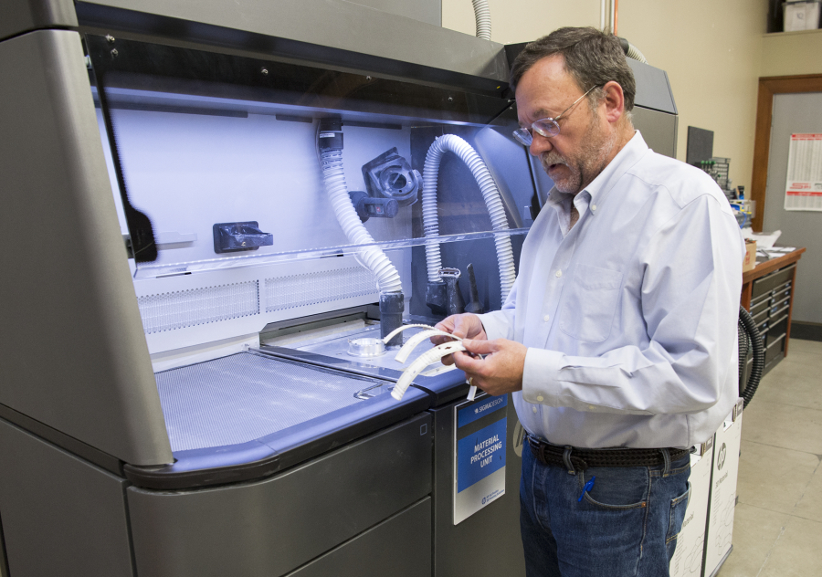 Sigma Design CEO Bill Huseby looks over parts created by the newest 3-D printer from HP Inc. Sigma Design representatives say the new technology allows it to start &quot;light manufacturing,&quot; making hundreds or thousands of parts for products.