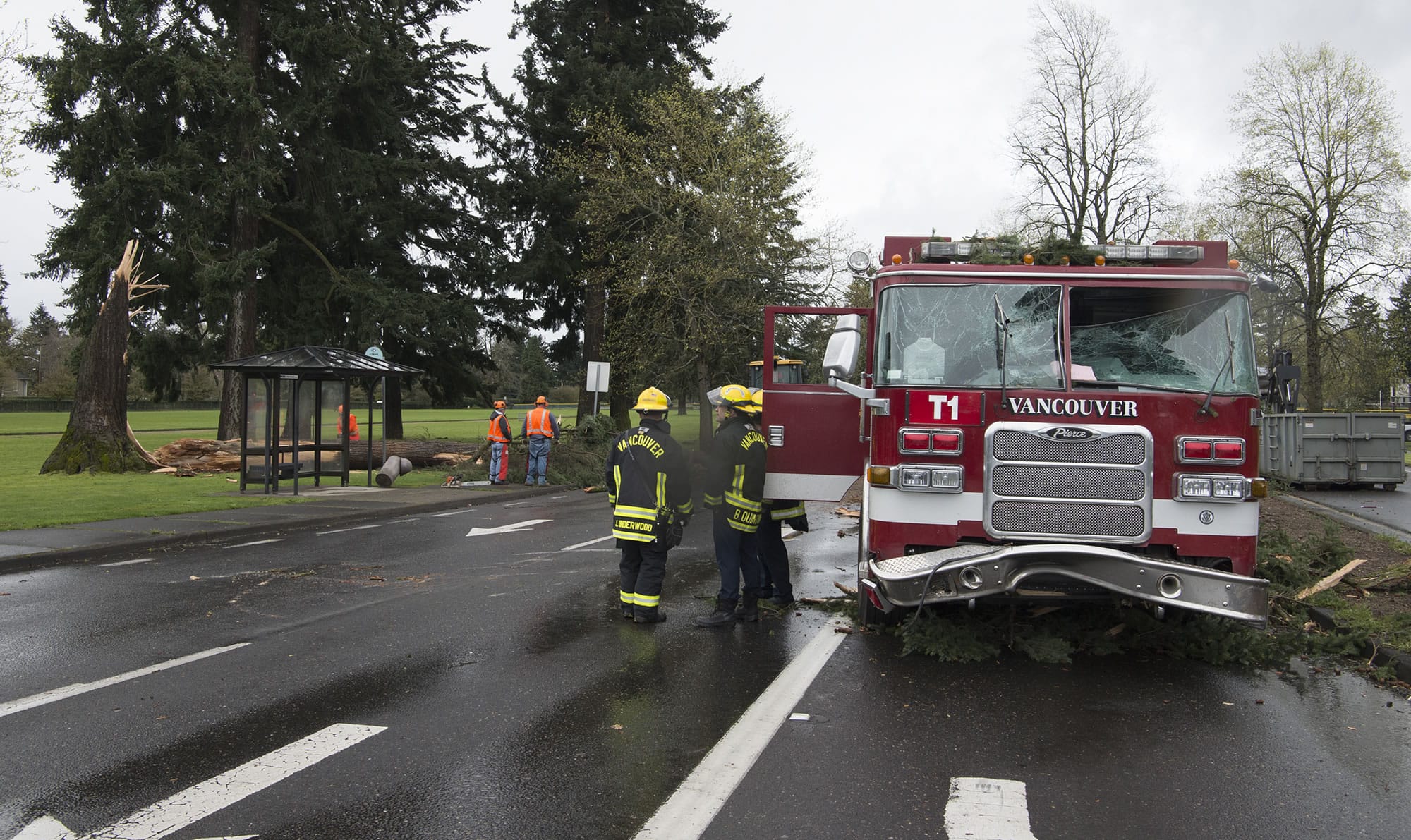 Crews work to clean up a large tree, left, after it fell on a Vancouver firetruck on East Mill Plain Boulevard following a windstorm Friday.