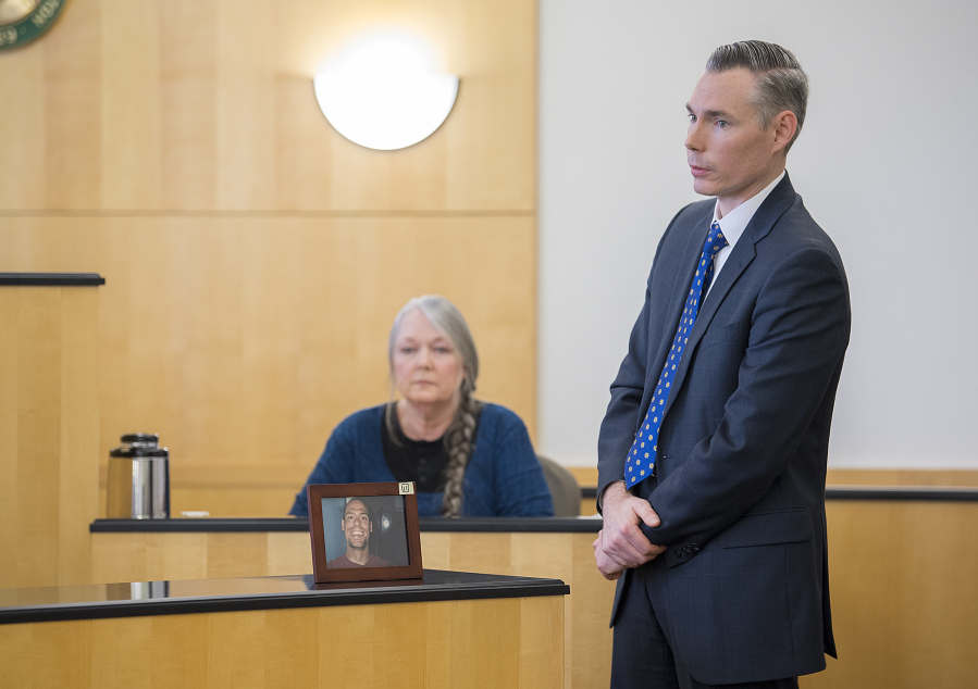 Deputy Prosecutor James Smith, right, speaks to the jury while displaying a framed photo of victim Brandon Maulding as his mother, Linda, background, testifies during Stephen Reichow&#039;s murder trial Thursday in Clark County Superior Court. Reichow is accused of beating Maulding to death with a baseball bat in August 2015 in Battle Ground.