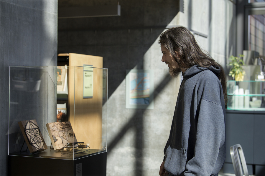 Local artist Jonathon David Turner looks over his wood-burning pictures on display at Vancouver Community Library as part of the Homeless not Hopeless art show.