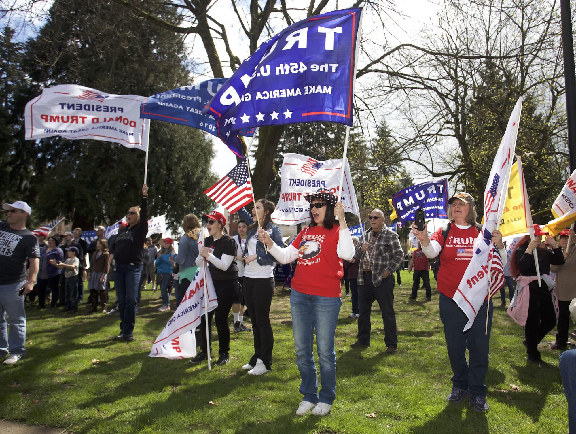 Cathy House of Tacoma, center, waves her flags along with others participating at a rally Sunday in support of President Donald Trump.