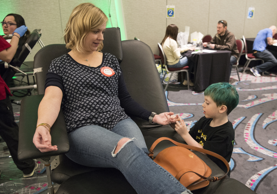 Declan Reagan, 5, holds Renee Eames&#039; hand and asks about the Band-Aid where Eames was pricked before donating blood at an event March 28 at The Nines hotel in Portland. The bone marrow and blood donation event was in honor of Declan, who was celebrating his fifth birthday. Declan was diagnosed last year with acute myeloid leukemia and recently relapsed.