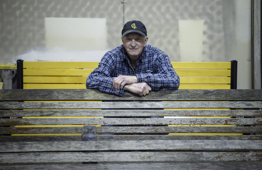 Sitting on a refurbished bench made with Alaska yellow cedar, volunteer Jim Bunzey leans forward on a weathered oak bench that he will restore in the workshop in the West Barracks&#039; old Post Hospital.