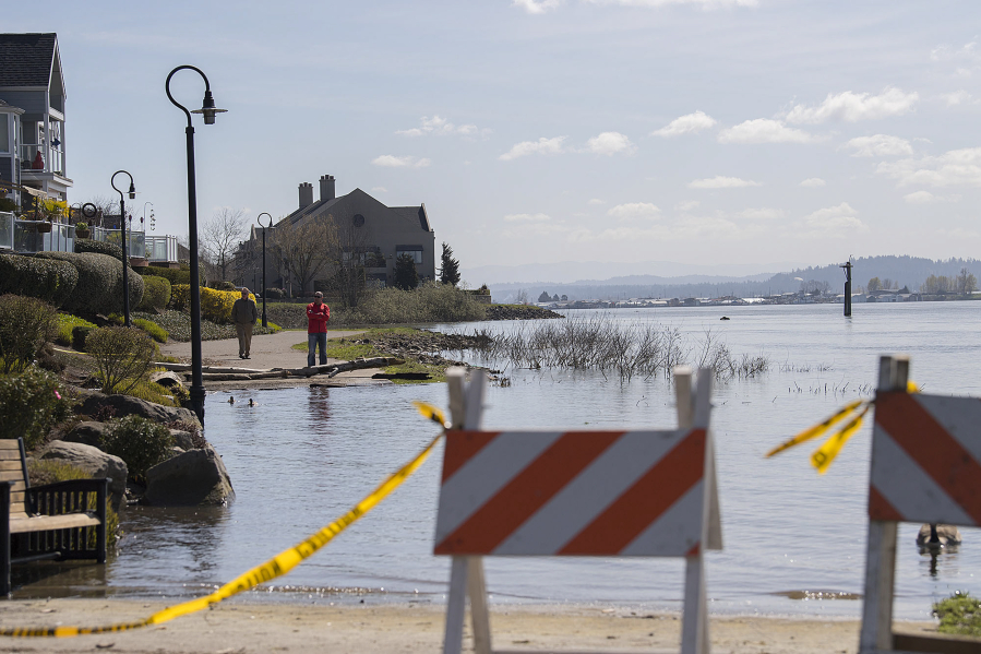 Barriers and caution tape are seen along the flooded section of the Waterfront Renaissance Trail near Columbia Shores Condominiums on Monday. The river has been at or near flood stage since March 16, but that is expected to end early Tuesday.