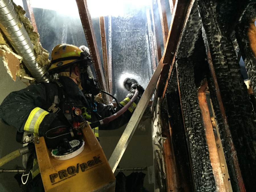 Firefighters deal with a fire that crept into a triplex&#039;s attic in east Vancouver, at 903 S.E. 152nd Ave., Monday afternoon. One woman was hospitalized with significant burns to her hands and arms as a result of the fire.