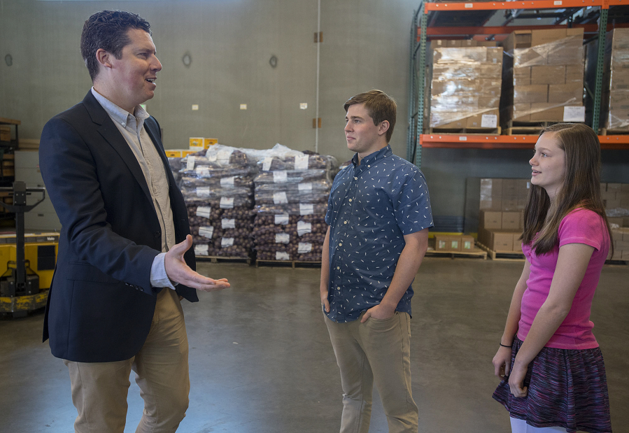 Matt Edmonds, communications manager for Clark County Food Bank, from left, chats with Aidan Ryan, 17, and his sister, Erin Ryan, 13, at the food bank&#039;s warehouse. The siblings helped raise $109,960 and collected 8,500 pounds of food split between the food bank and St. Vincent de Paul.