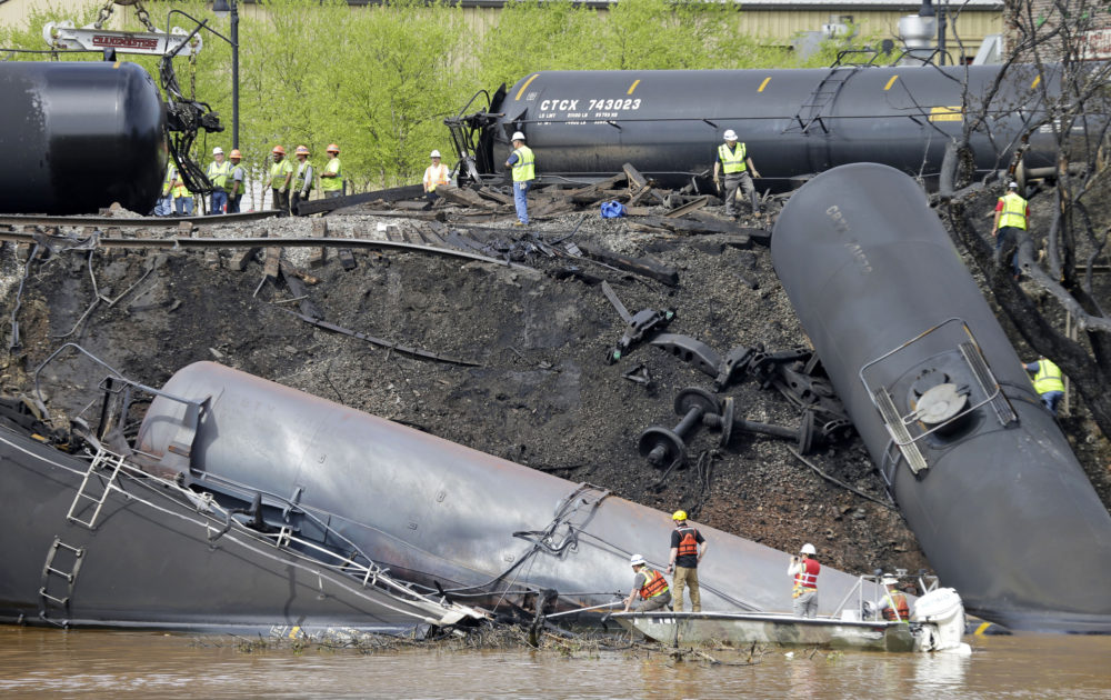 FILE - In this May 1, 2014, file photo survey crews in boats look over tanker cars as workers remove damaged tanker cars along the tracks where several CSX tanker cars carrying crude oil derailed and caught fire along the James River near downtown Lynchburg, Va. Inspectors have found almost 24,000 safety defects over a two-year period along United States railroad routes used to ship volatile crude oil. Data obtained by The Associated Press shows many of the defects were similar to problems blamed in past derailments that caused massive fires or oil spills in Oregon, Virginia and Montana.