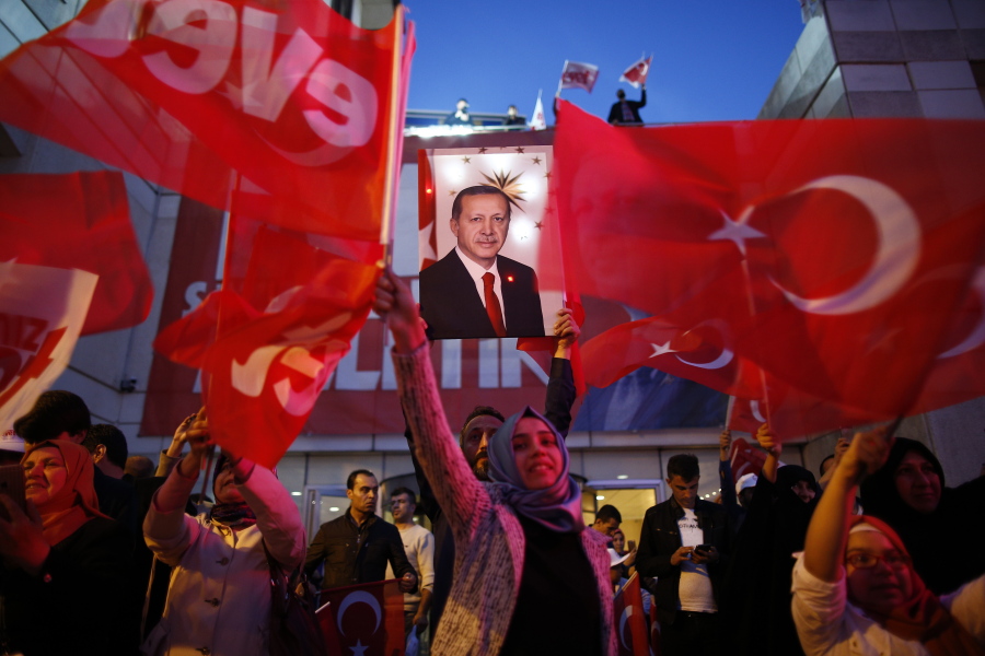 Supporters of Justice and Development party wave Turkish flags and hold a poster of Turkish President Recep Tayyip Erdogan outside its offices in Istanbul, on Sunday.