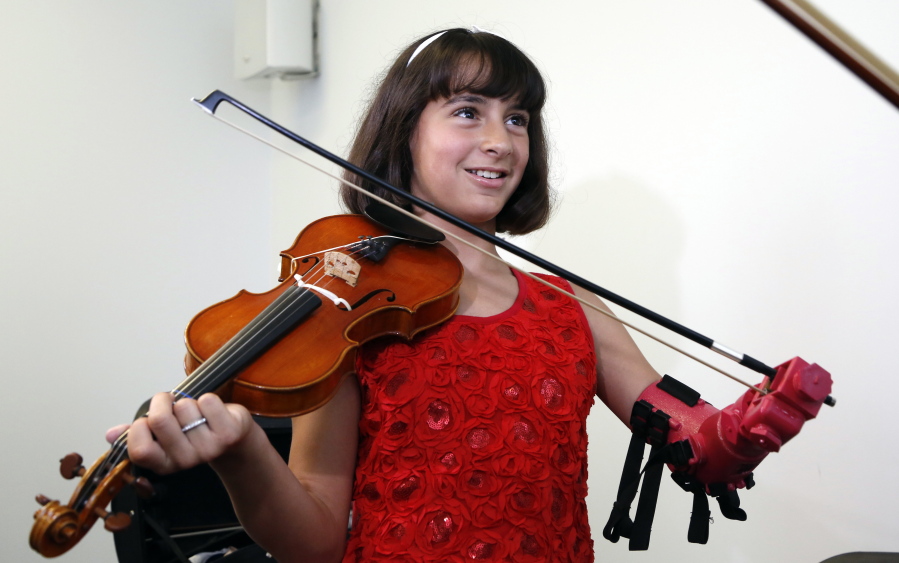 Isabella Nicola Cabrera, 10, plays her violin with her new prosthetic Thursday at the engineering department of George Mason University in Fairfax, Va. &quot;Oh my gosh, that&#039;s so much better,&quot; Isabella said as she tried it out.