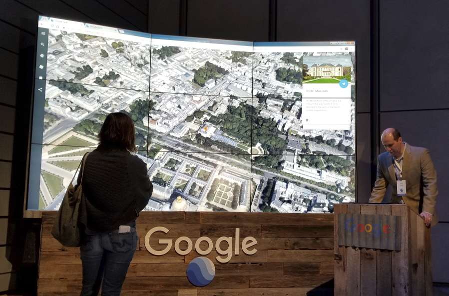 Sean Askay, right, engineering manager with Google Earth, demonstrates new features on Google Earth, displayed in background, on April 18 in New York.